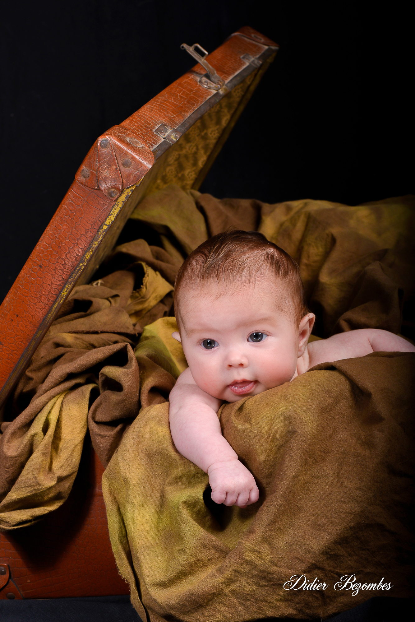 portrait-de-bébé-dans-une-valise-photos studio original-en-couleur-sur-fond-noir-photographe-Didier-Bezombes