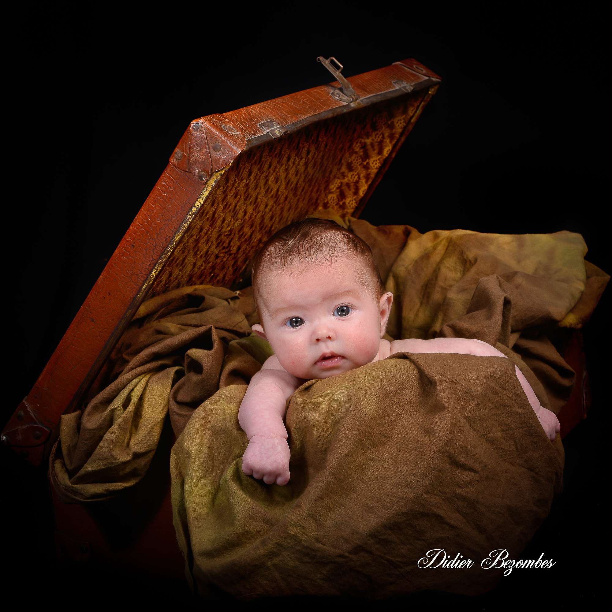 portrait-de-bébé-dans-une-valise-photos studio original-en-couleur-sur-fond-noir-photographe-Didier-Bezombes