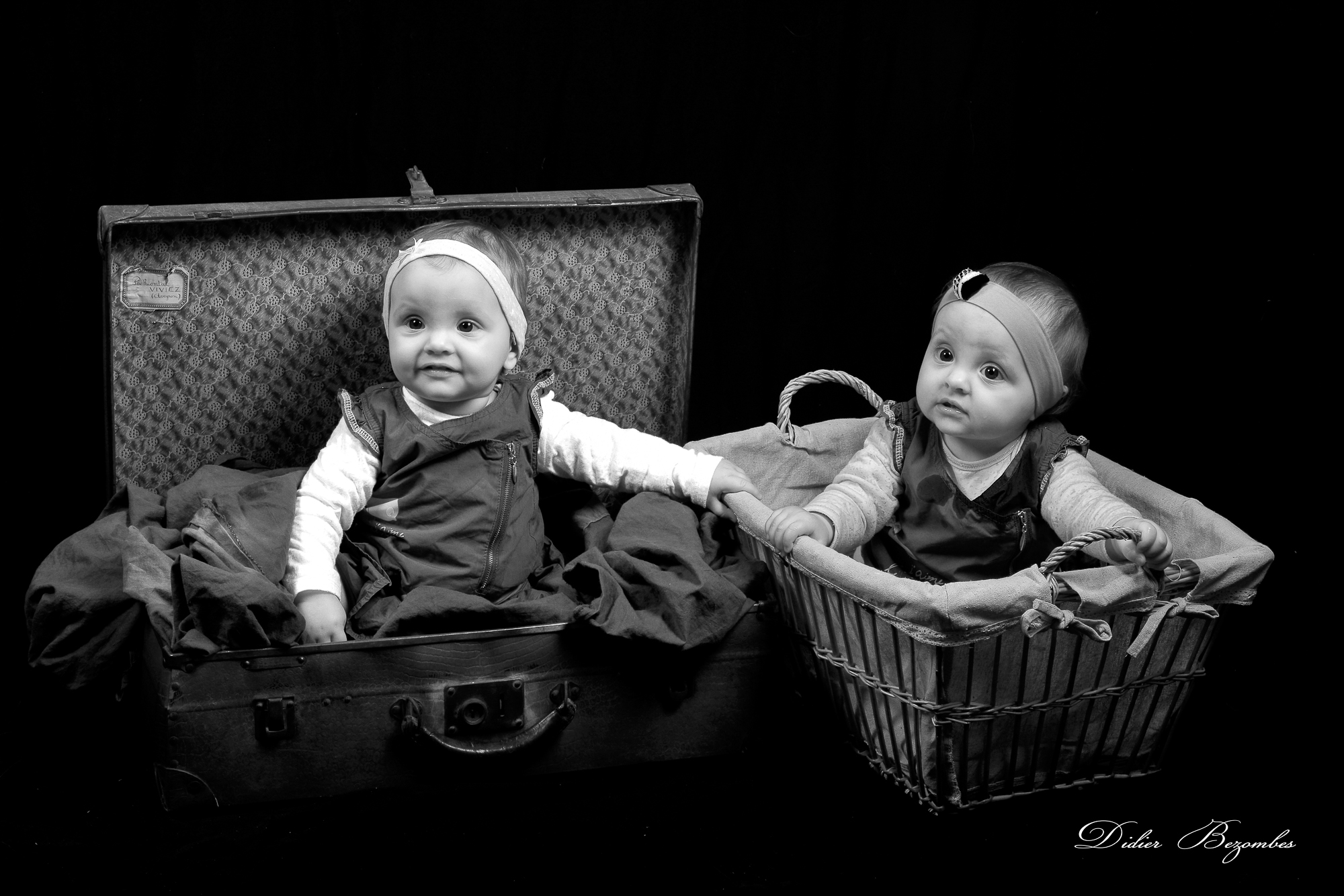 portrait-de-bébés-jumelles-dans-une-valise-photos studio original-en-noir-et-blanc-sur-fond-noir-photographe-Didier-Bezombes