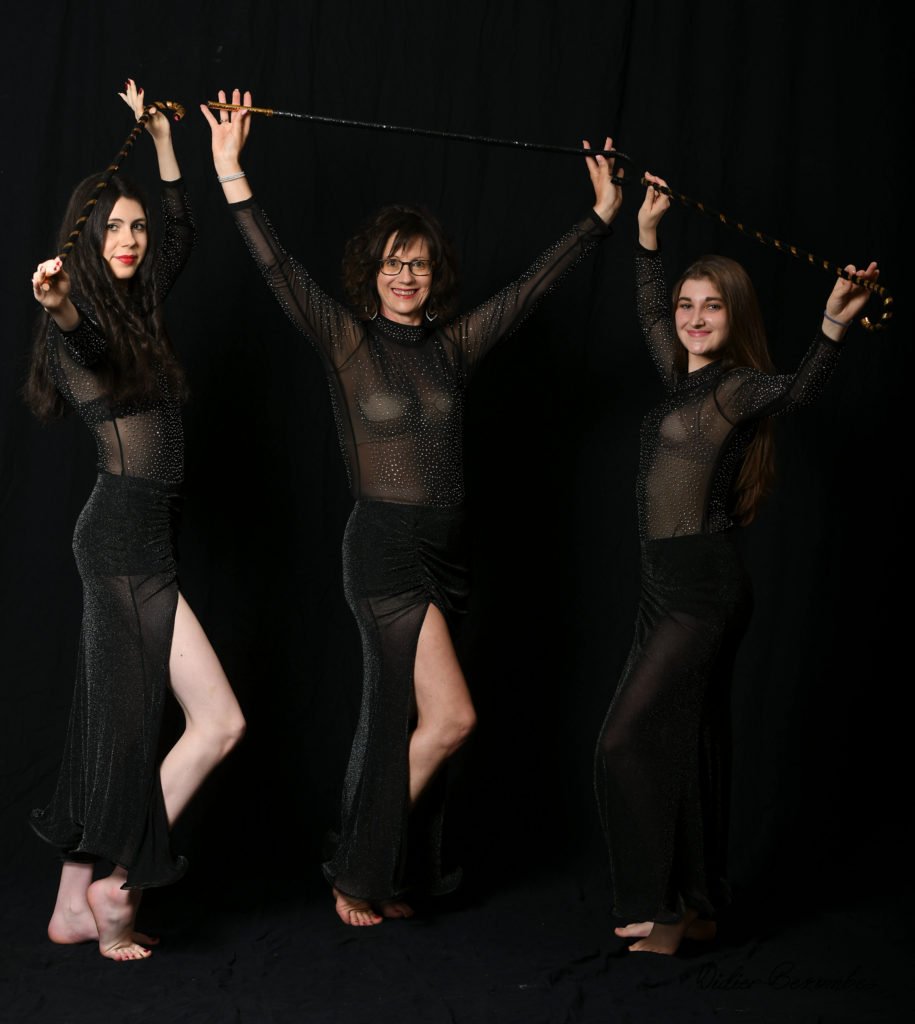 photo en studio de trois danseuses orientale le fond est noir les robes noir les danseuses on une canne comme accessoire quelles tiennent au dessus de leurs têtes elles sont   très souriante elle à été photographier par Didier Bezombes photographe à Rodez en Aveyron