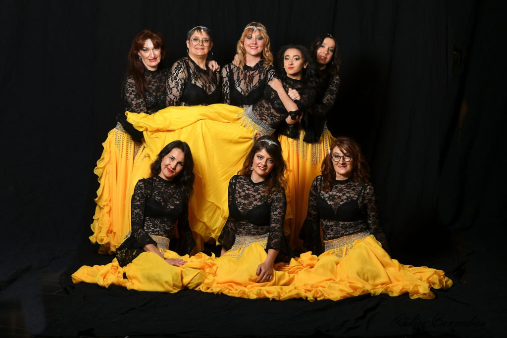 photo en studio d'un groupe de danseuses orientale le fond est noir les robes sont jaune et les bustiers en dentelles  noir les danseuses sont   très souriante elle à été photographier par Didier Bezombes photographe à Rodez en Aveyron