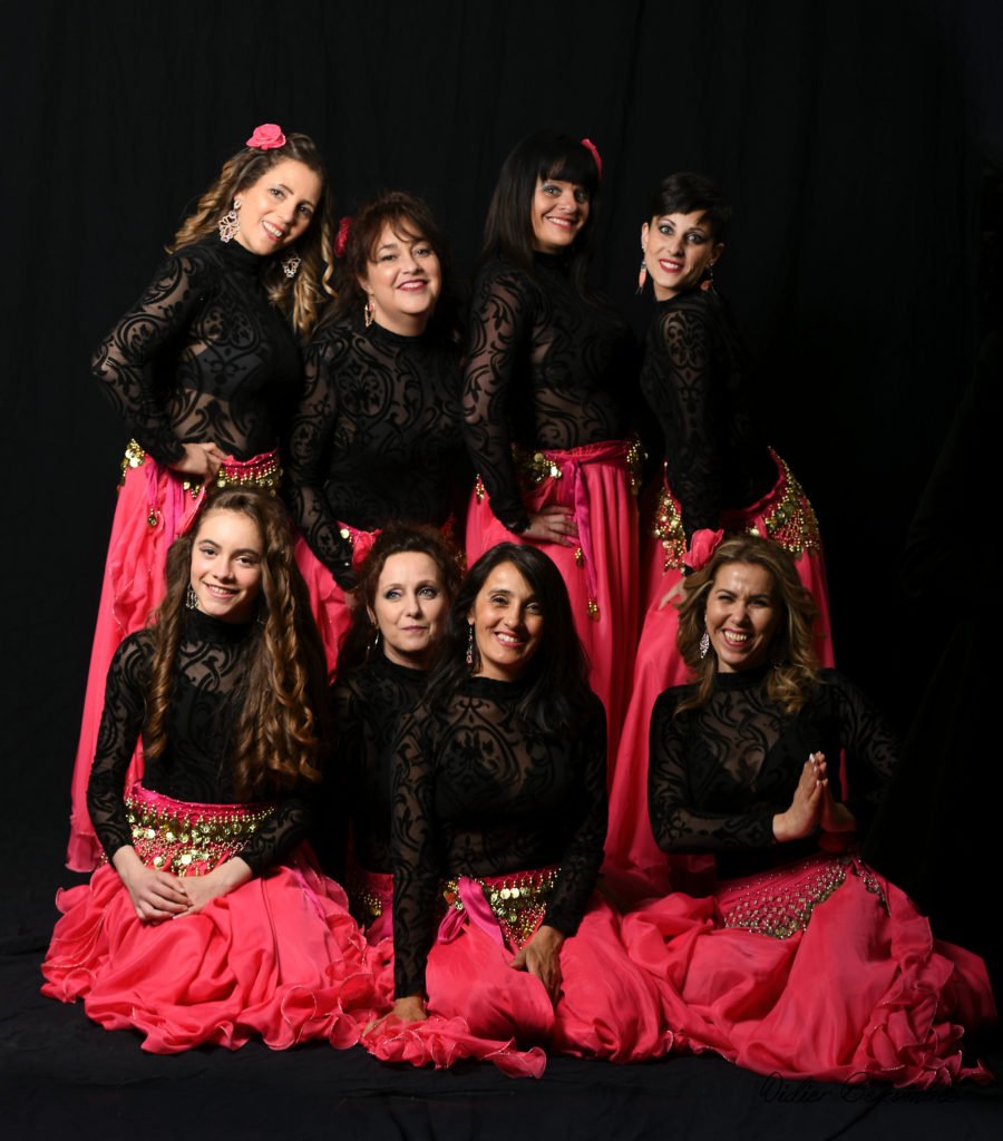 photo en studio d'un groupe de danseuses orientale le fond est noir les robes sont rose et les bustiers en dentelles  noir les danseuses  sont   très souriante elles ont été photographier par Didier Bezombes photographe à Rodez en Aveyron