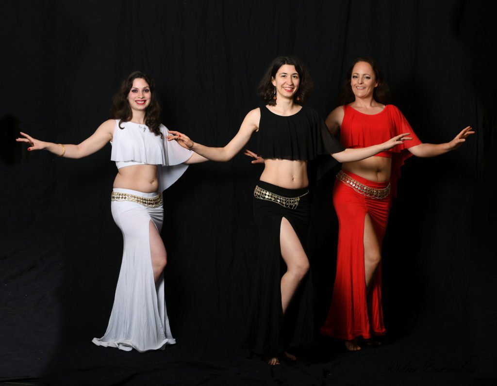 photo en studio de 3 danseuses orientale le fond est noir elles portent des robes de couleur différente il y a de gauche à droite une blanche ,une noir et une rouge les danseuses  sont   très souriante elles ont été photographier par Didier Bezombes photographe à Rodez en Aveyron