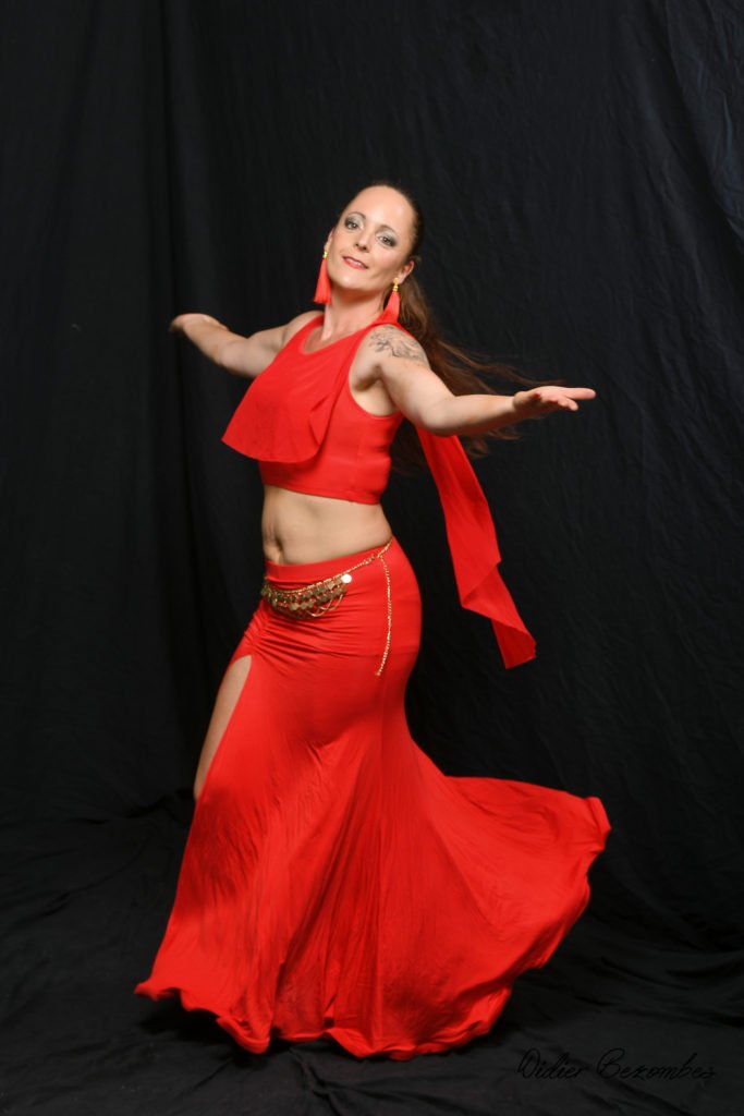 photo en studio de 1 danseuse orientale le fond est noir elle une robe rouge la danseuse est très souriante elle a été photographier par Didier Bezombes photographe à Rodez en Aveyron